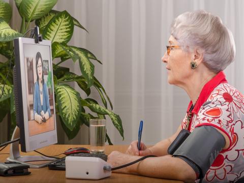 Older woman telemedicine wearing blood pressure cuff