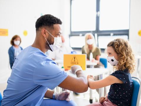 Vaccinator giving young girl elbow bump