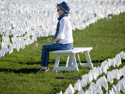 Woman sitting among white COVID flags