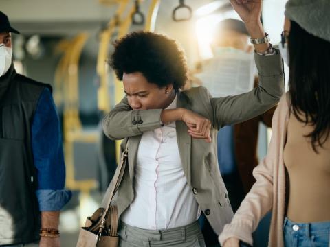 Woman coughing into sleeve on train