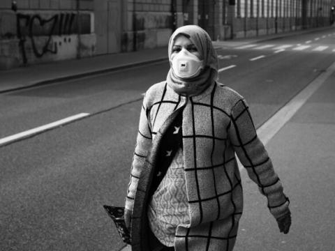 Lone woman with mask walking along street