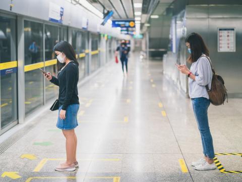 Women physically distancing at train station