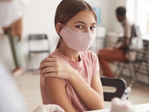 Young masked girl at vaccine center