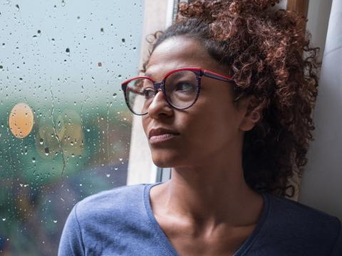 Sad young woman by rainy window
