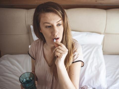 Young woman taking a white pill