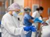 Three healthcare workers putting on personal protective equipment