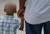Back view of little boy holding his dad's hand