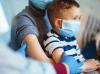 Boy on mom's lap with vaccine bandage on arm