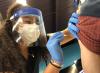 COVID vaccinator wearing mask, face shield