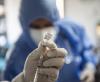COVID vaccine with blurred healthcare worker in background