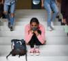 Depressed teen girl wearing mask on school stairway