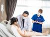 Doctor and nurse checking on girl in hospital bed