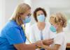 Doc with stethoscope examining child wearing a mask