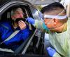 Woman in car gettnig nasal swab COVID test