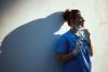 Exhausted health worker taking off mask, leaning on wall