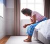 Exhausted woman sitting on edge of bed