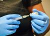 Gloved hands drawing COVID vaccine into syringe