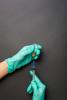Gloved hands preparing vaccine in syringe