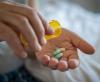 Green and white capsules in person's hand