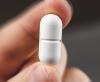 Hand holding a white pill