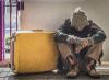Dejected homeless man sitting on sidewalk