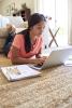 Teen on floor doing homework on laptop