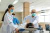 Healthcare workers help move a patient in a hospital bed