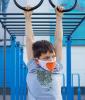 Boy wearing mask and hanging on rings