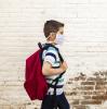 Masked school boy with backpack