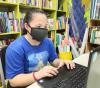 Mask-wearing student at laptop in library