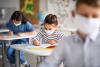 Masked schoolkids at desks