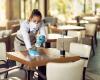 Masked waitress cleaning table