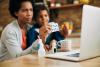 Mom holding capsules with boy at computer