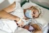 Mom wearing mask nursing newborn baby