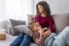 Mom taking temperature of sick boy on couch