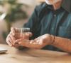 Older man taking 2 white pills