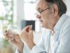Older man taking white pill