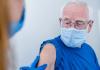 Older man in mask getting vaccinated