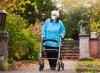 Older woman wearing mask outside using walker