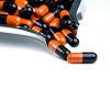 Orange and black capsules on production line