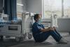 Sad nurse next to empty hospital bed