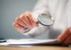 Scrutinizing report with magnifying glass