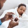 Sick girl in bed with dad taking her temperature