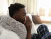 Sick man on couch blowing nose