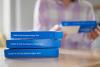 Stack of rapid COVID tests, woman in background
