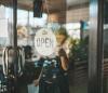 Store owner with mask and "open" sign