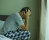 Stressed man sitting on edge of bed