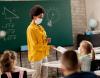 Masked teacher handing out a test