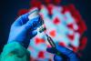 Vaccine vial and syringe in front of a virus image