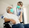 Wheelchair patient with doctor, both wearing masks